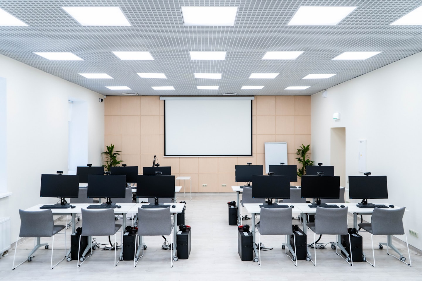 Modern computer lab with rows of computers and chairs.